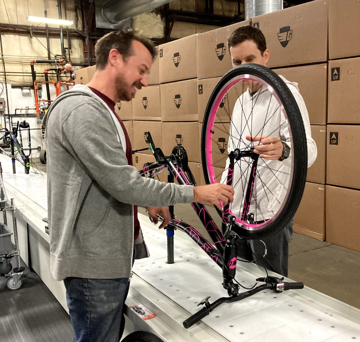 Two Guardian employees assembling a bike on the assembly line
