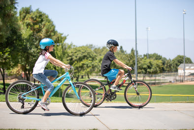 Two kids ride 24" Guardian Bikes in the park